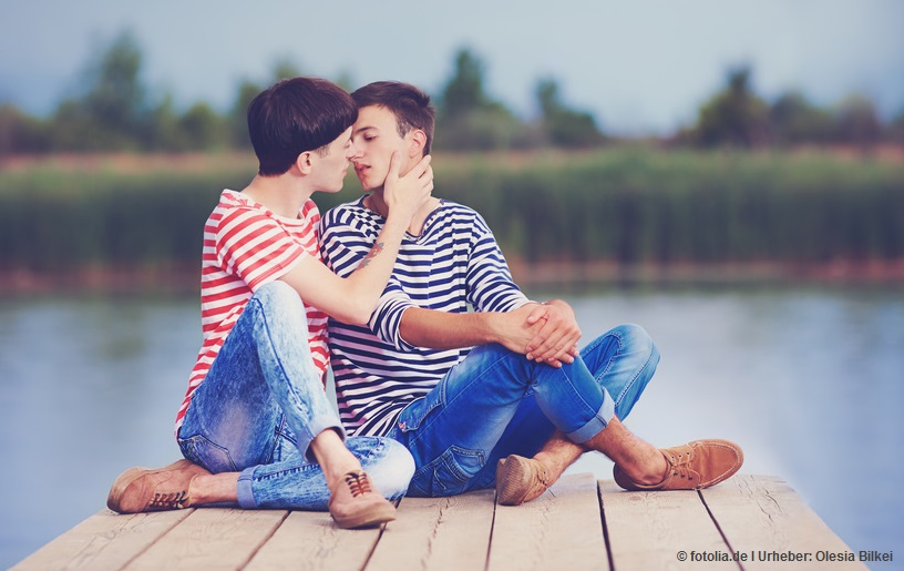 gay couple kissing on wooden pier at riverbank