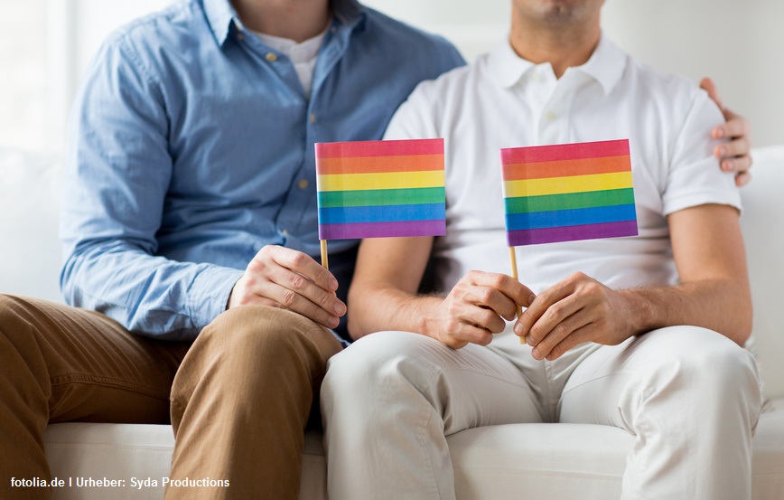 close up of male gay couple holding rainbow flags
