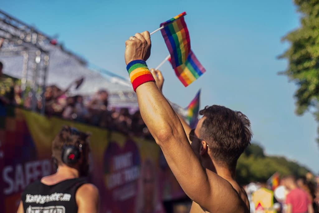 Menschen beim CSD Dresden: Eine Person hält eine Regenbogenfahne in die Höhe.