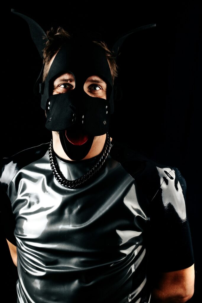 A person wearing black latex clothing and a black mask