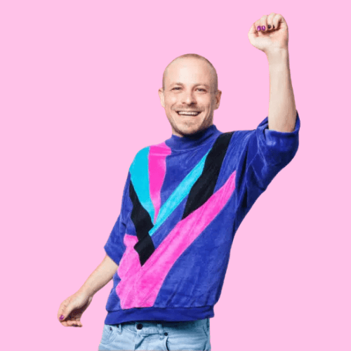 Frontalaufnahme von Robi mit farbenfrohem Oberteil – inspiriert von den Farben der Inter- und Trans-Flaggen.