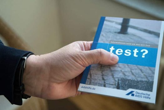 One hand holds an HIV self-test with the inscription "Go for a test!" - Reminder to test regularly as part of safer sex.