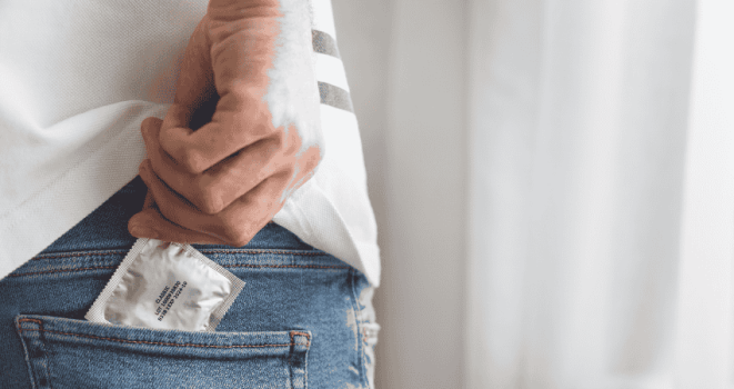 A person takes a condom out of their trouser pocket - symbolising preparation for safer sex.