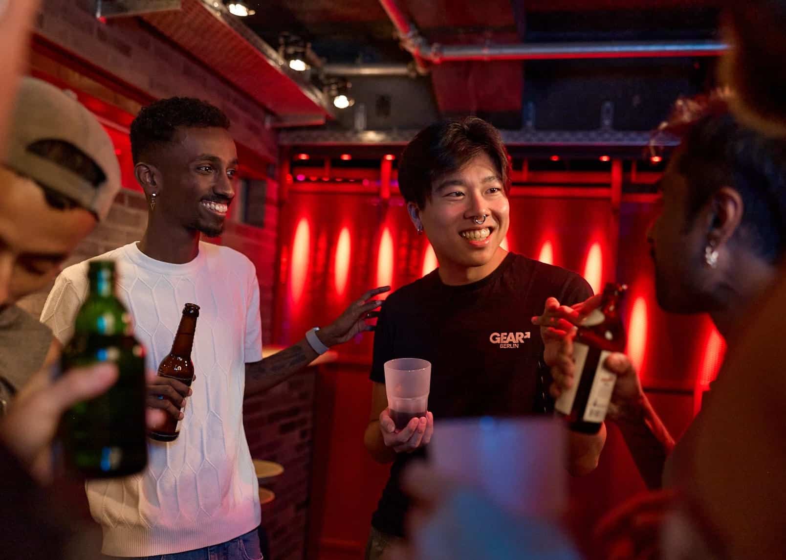 queere Männer unterhalten sich lachend in einer Bar – Community-Moment aus dem Gay Magazin