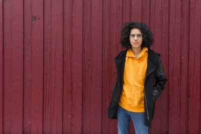 Lizzy stands confidently in front of a red wooden wall