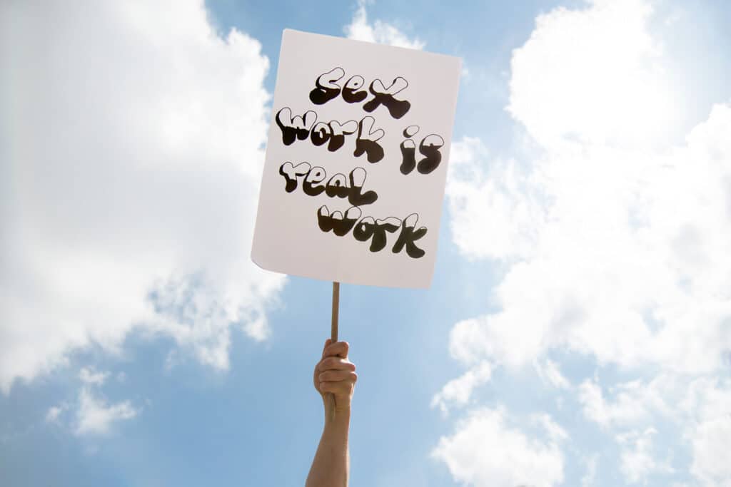 Hand hält ein Protestschild mit der Aufschrift „Sexwork is Work“ bei einer Demo für die Rechte von Sexarbeiterinnen und Sexarbeitern in Berlin.